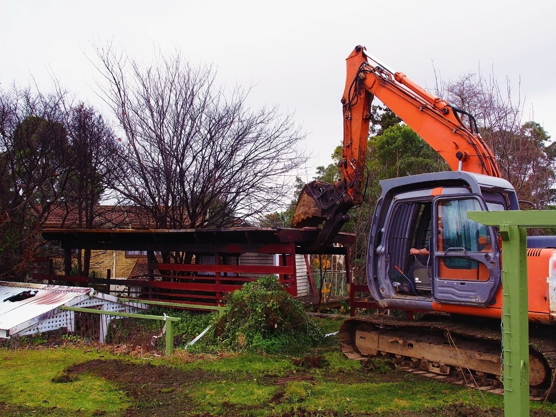 An orange excavator is digging a hole in a grassy field