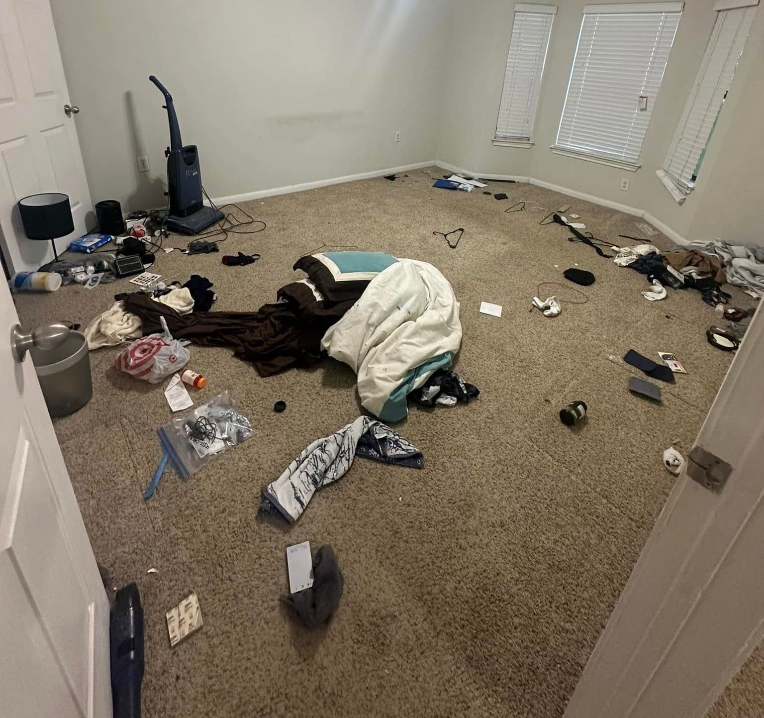 A messy room with a ceiling fan and a vacuum cleaner.