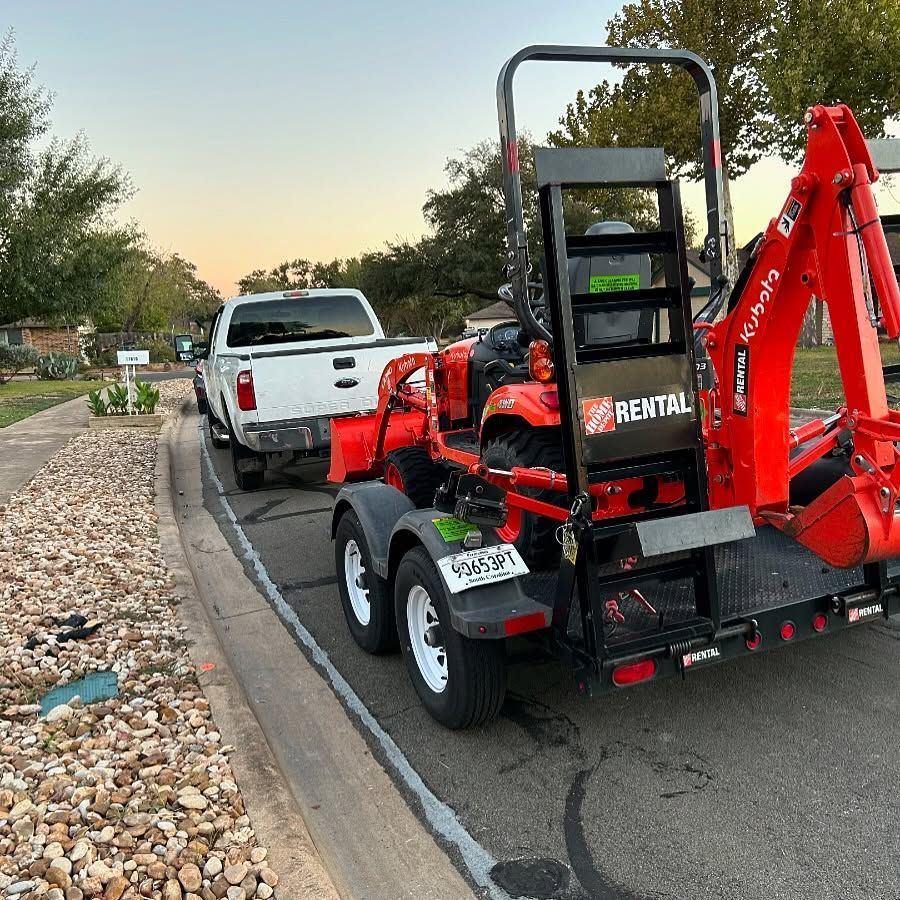 A truck is towing a tractor on a trailer.