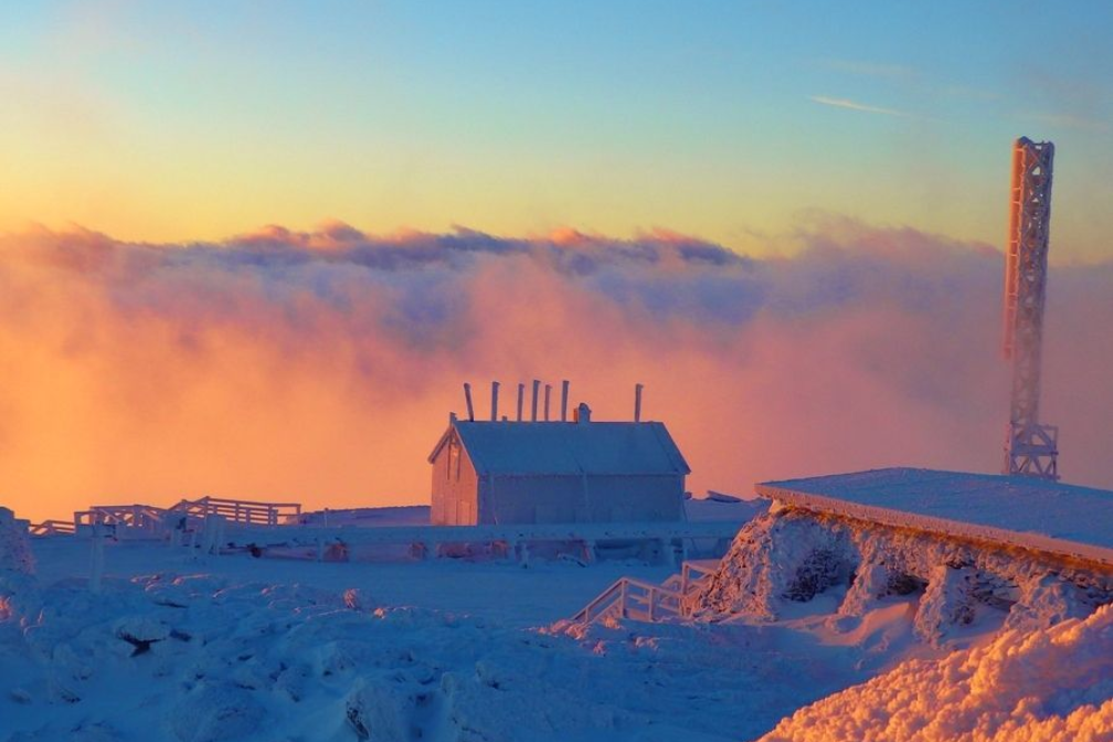 Snow covered weather observatory with pink clouds in the sky