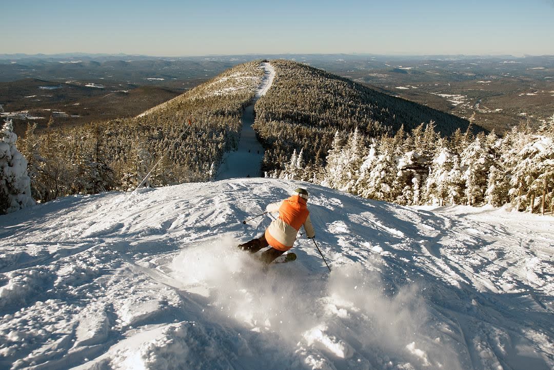 Skier at Cannon Mountain with snowy peaks in the White Mountains, New Hampshire.