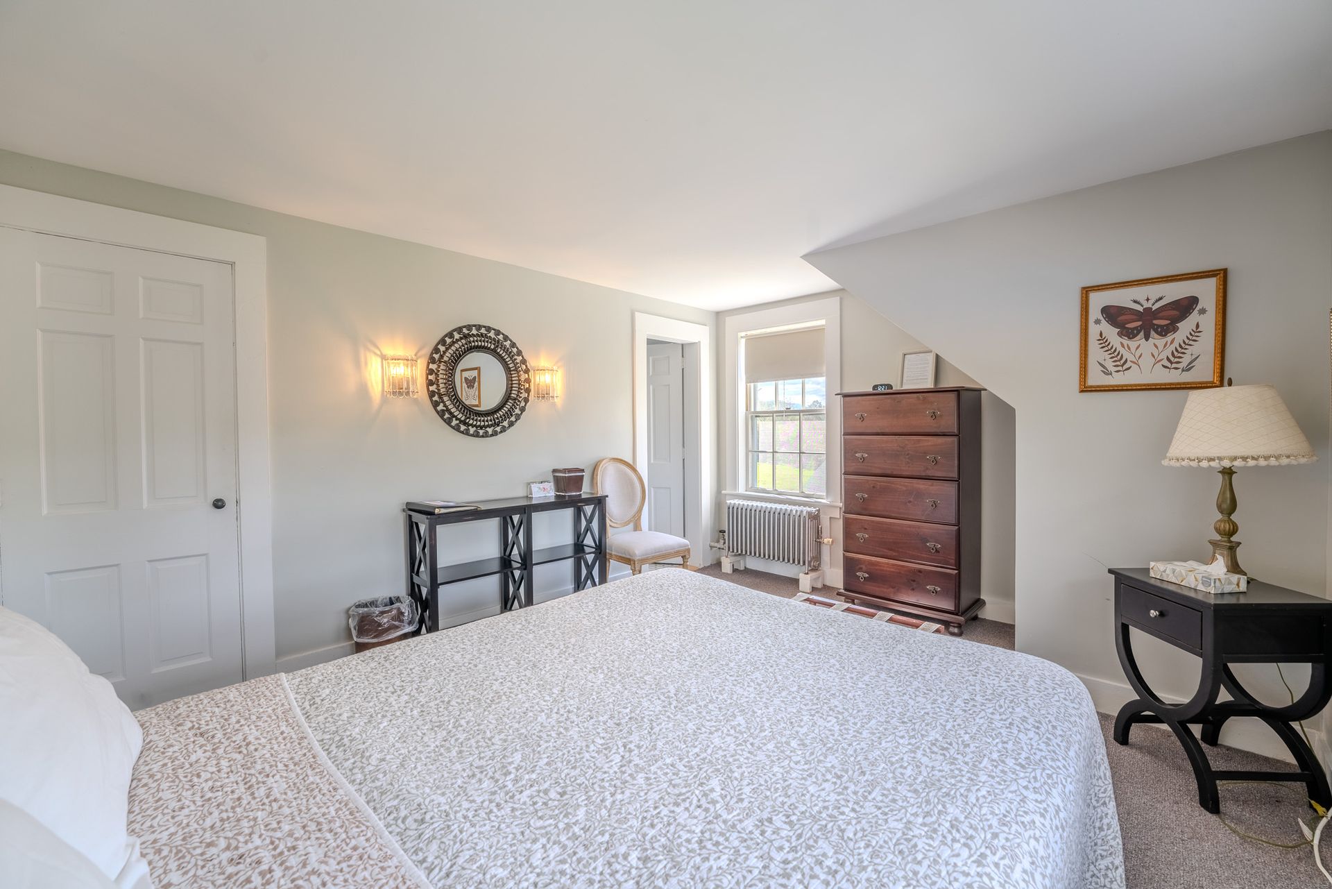 Bedroom with white bedspread, black furniture, and light gray walls.