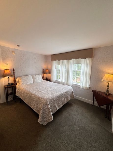 Bedroom with a bed, two bedside tables with lamps, and a window with curtains.