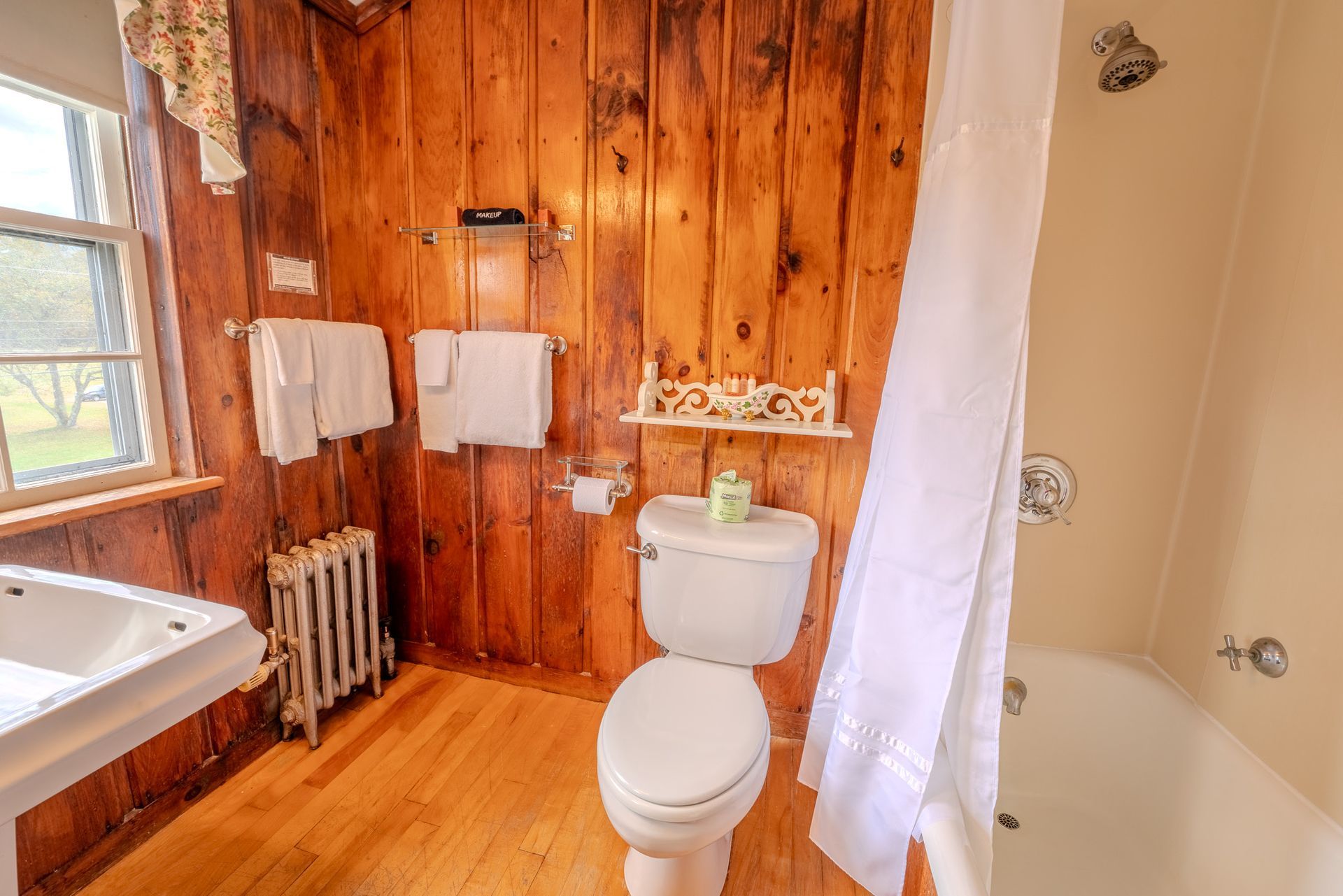 Bathroom with wood paneling, white fixtures, and a window.
