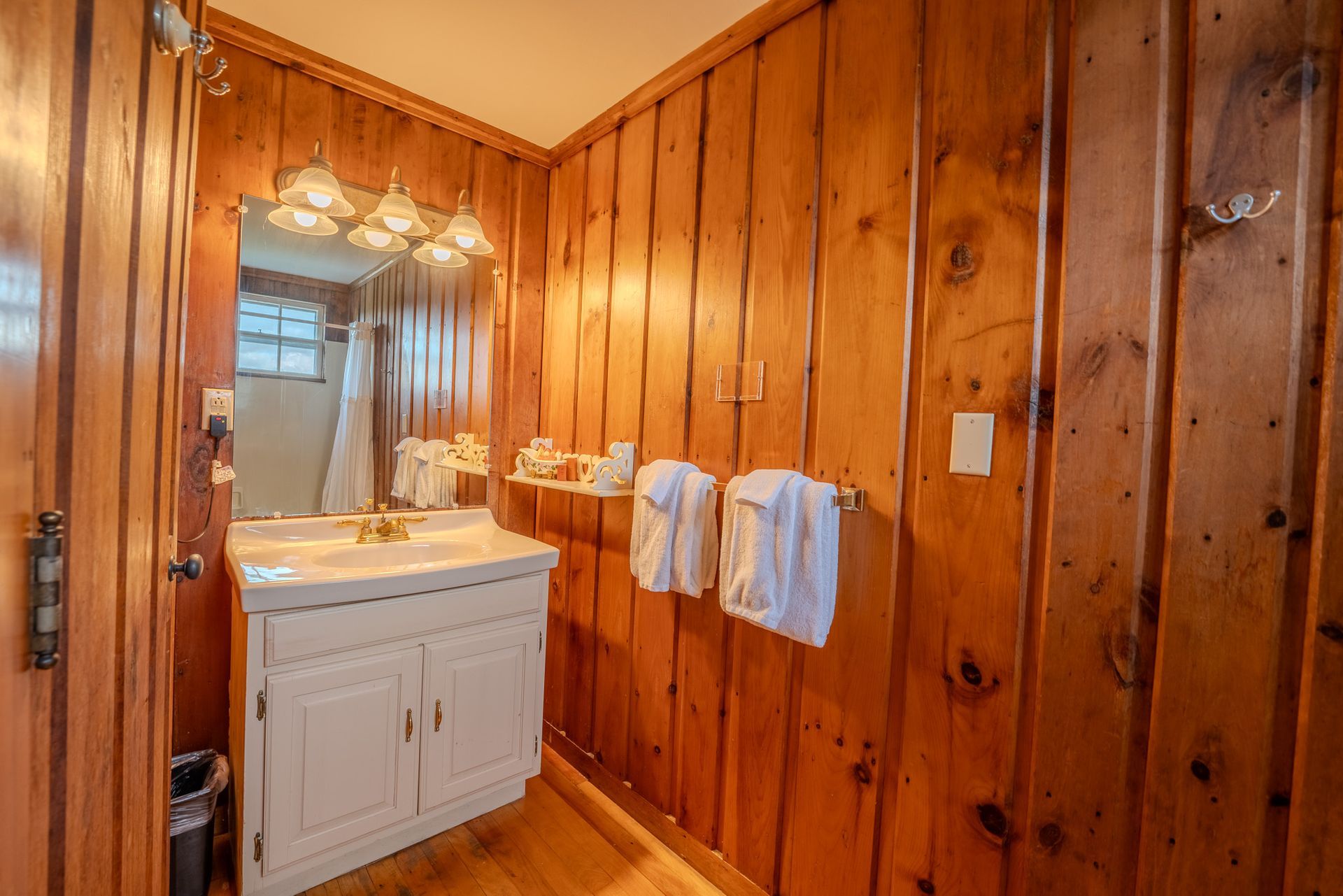 Small bathroom with wood-paneled walls, a white sink cabinet, and white towels.