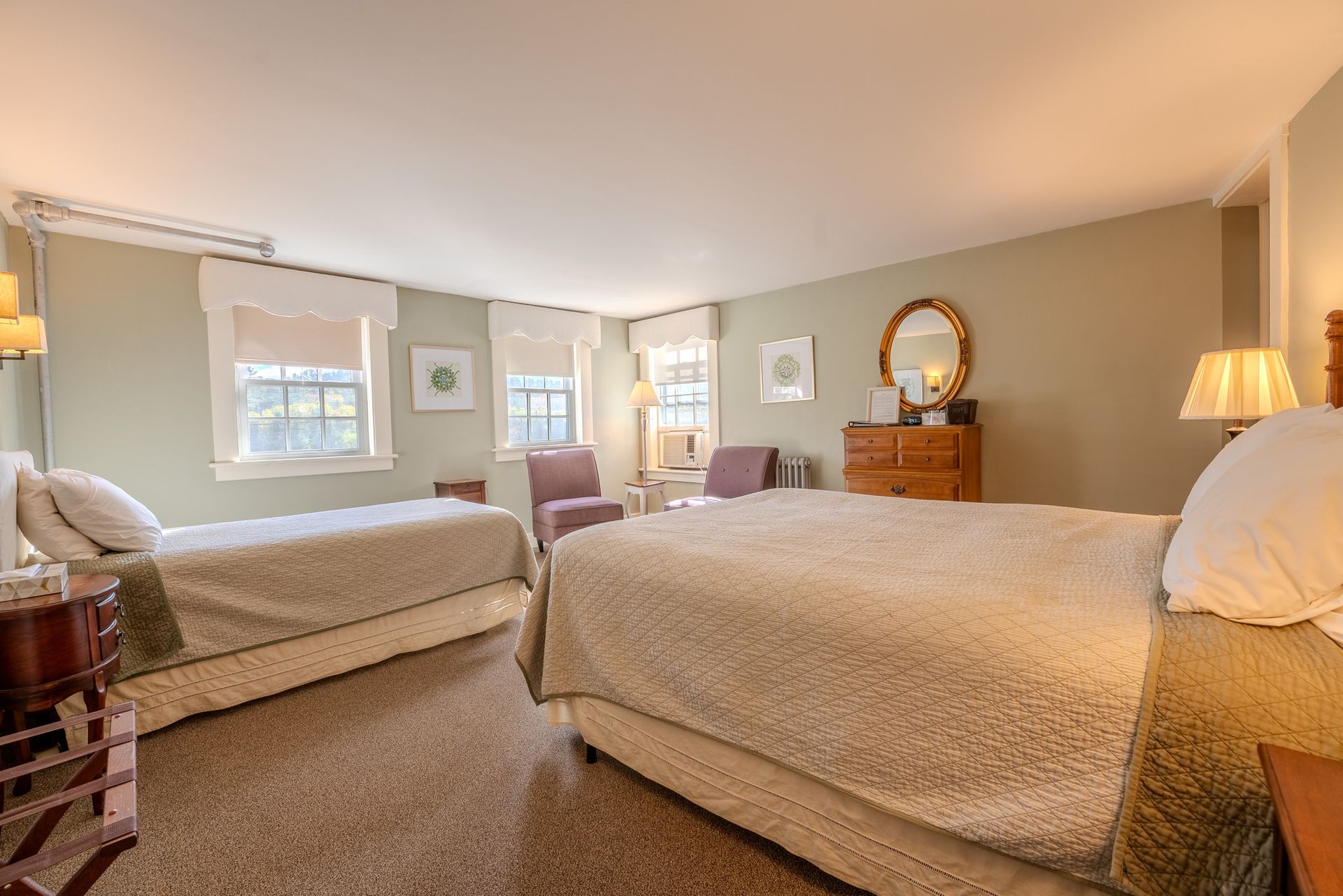 Bedroom with two beds, two chairs, and dresser. Beige and muted green color scheme.