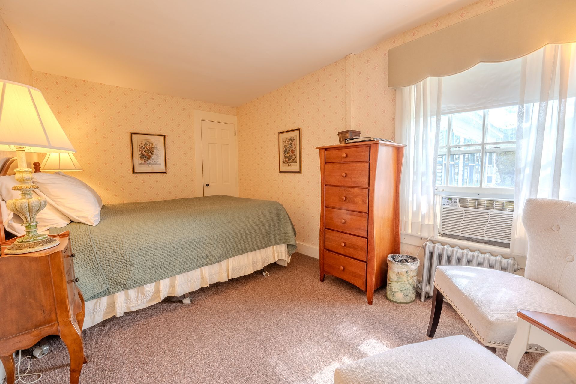 Bedroom with a single bed, dresser, two chairs, a window, and a lamp.
