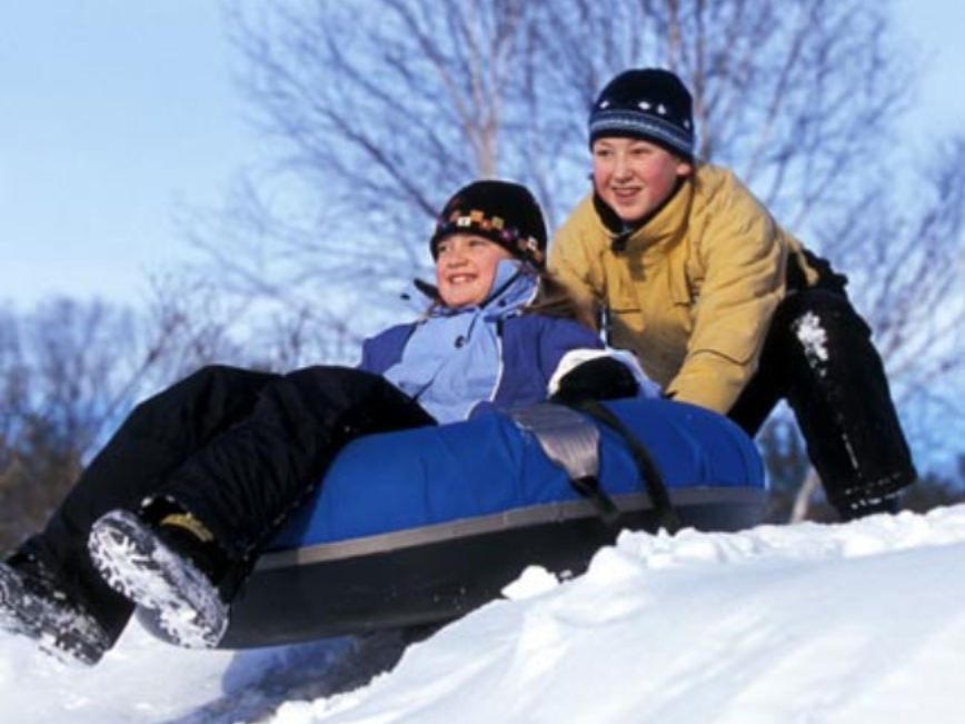 A young girl in a white dress stands at the edge of a pool, looking down; lounge chairs in the background.