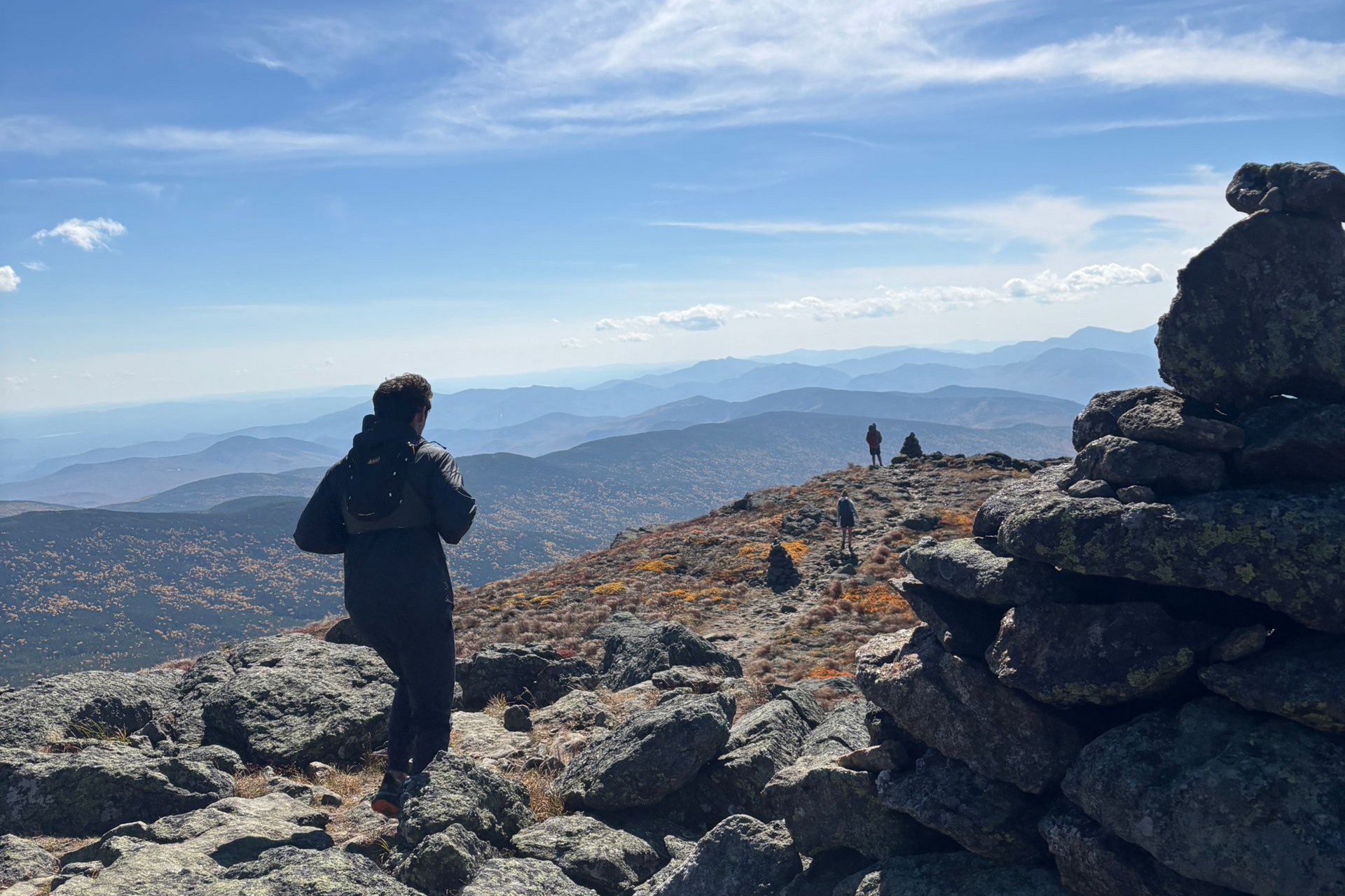 Hikers on top of a mountain ridge with mountains in the distance