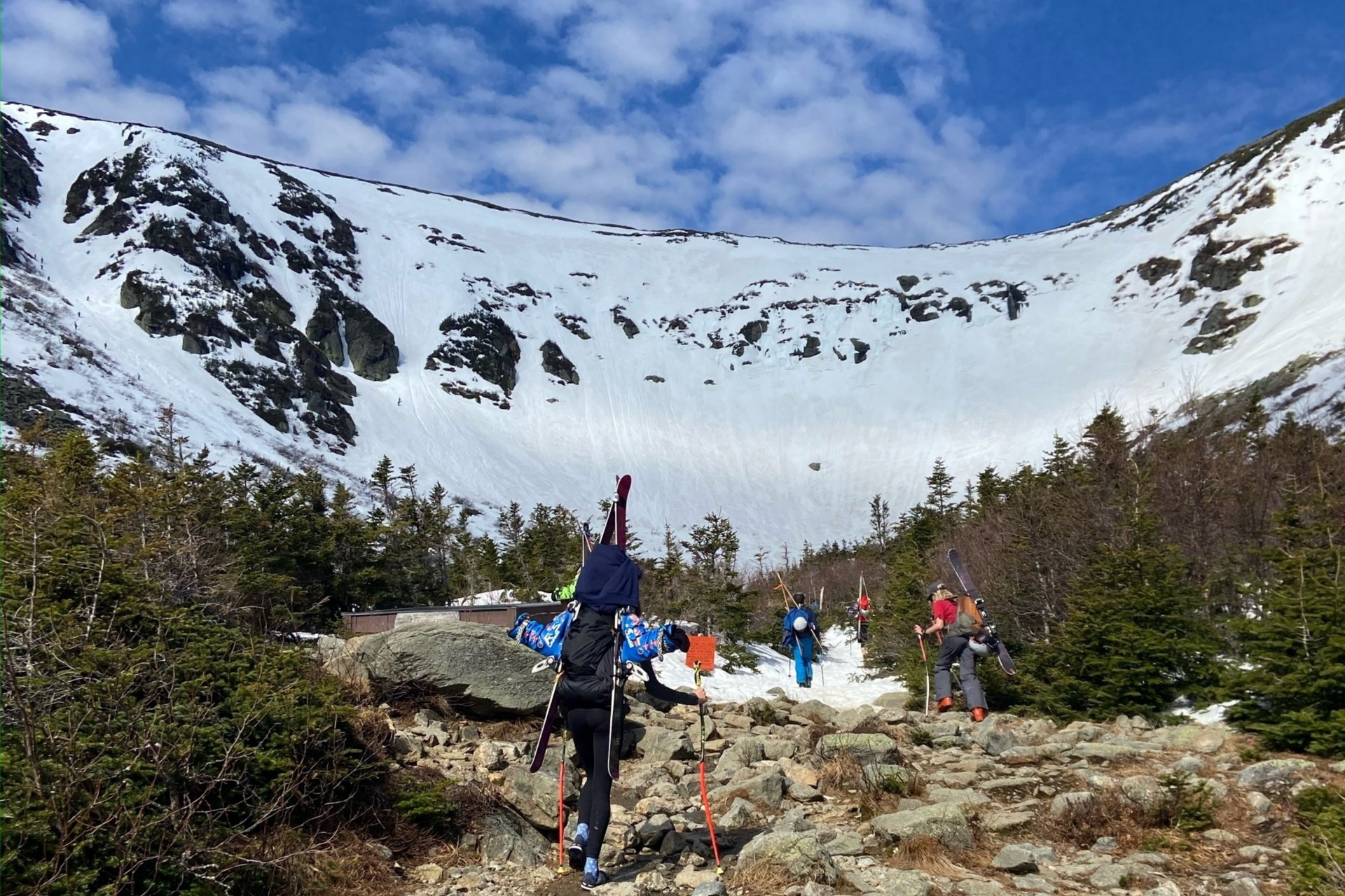 skiers looking up a a mountain ravine with snow