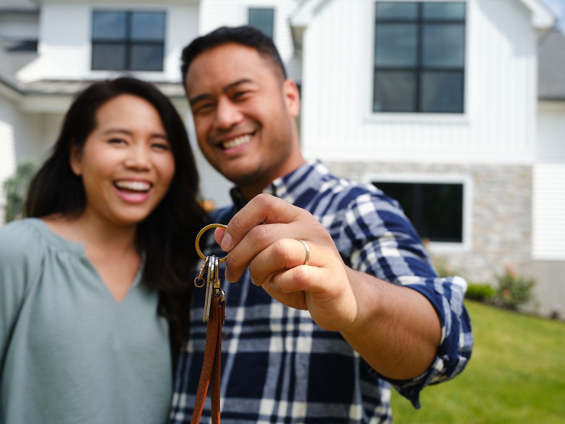 A man and woman are holding the keys to their new home.