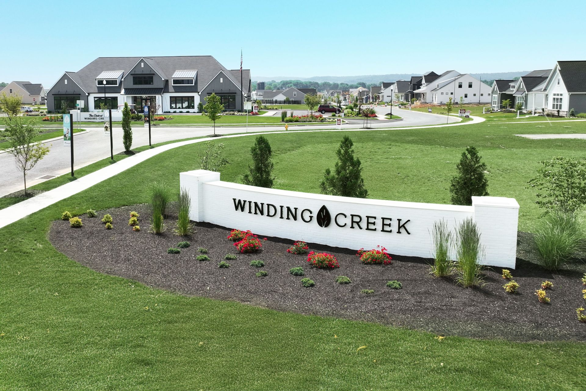 A sign for winding creek is in the middle of a lush green field.