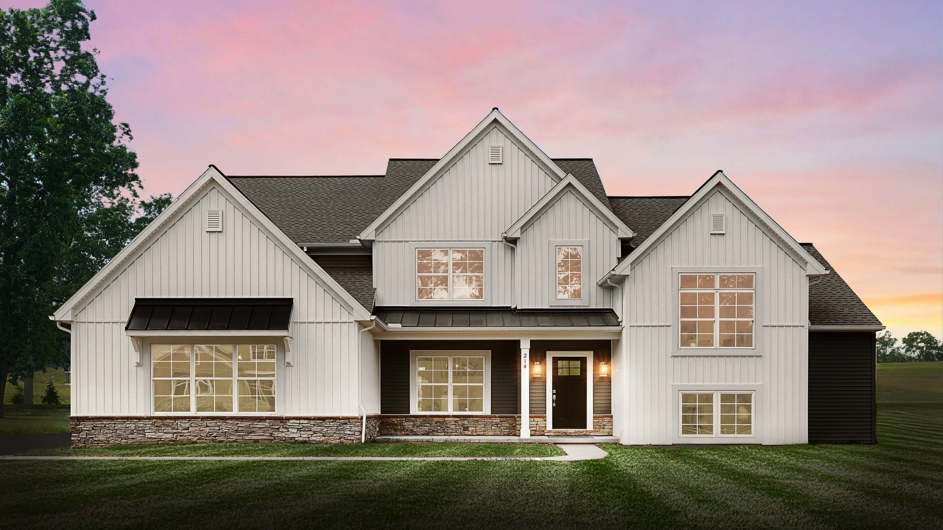 A large black and white house with a lot of windows is sitting on top of a lush green field.