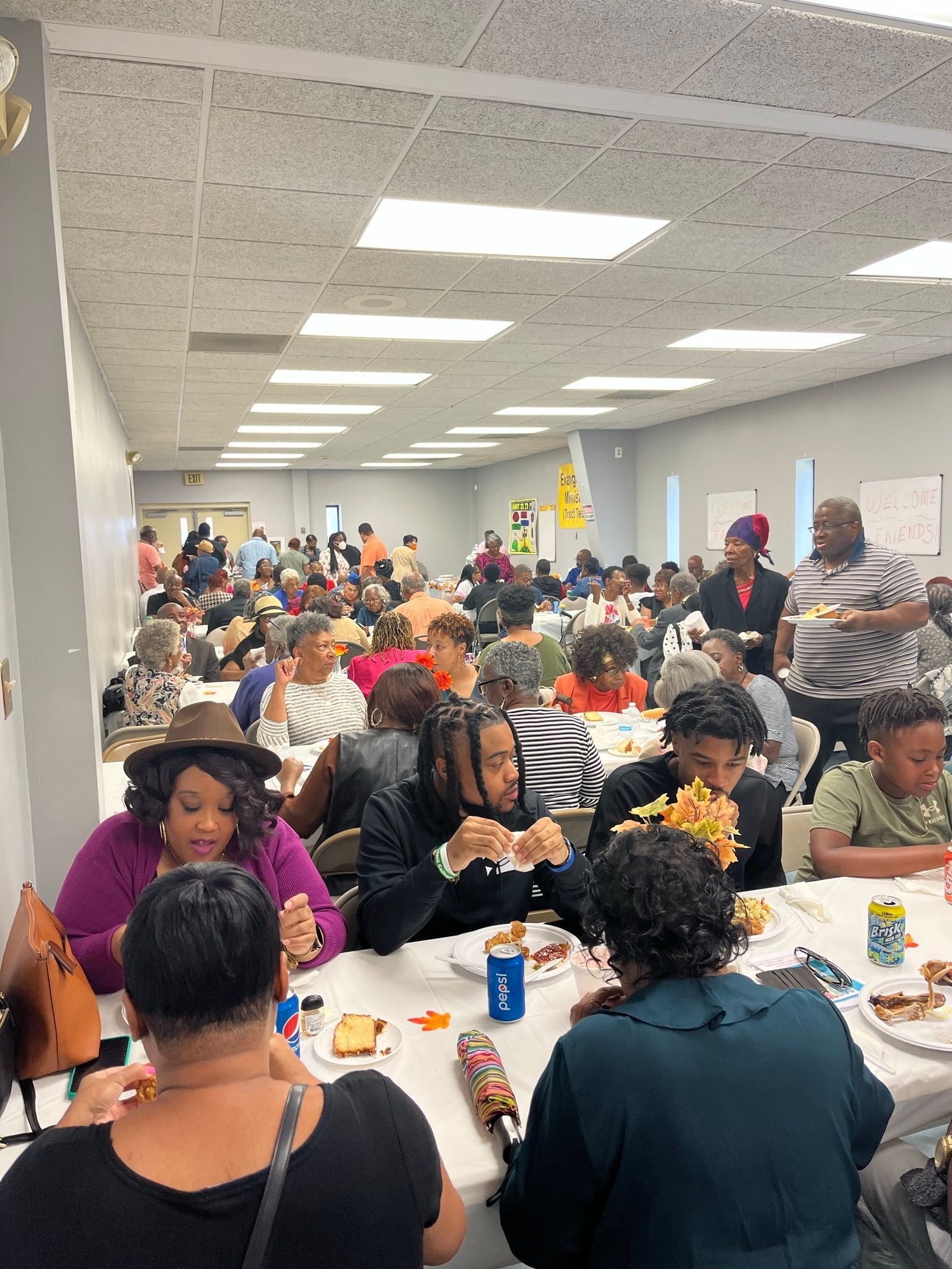 A large group of people are sitting at tables eating food.