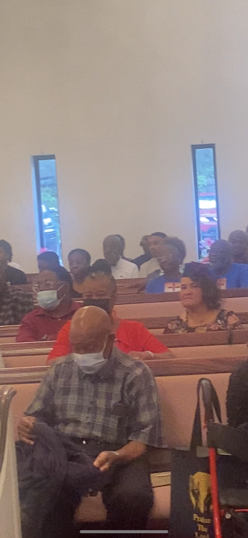 A group of people are sitting in a church wearing face masks.