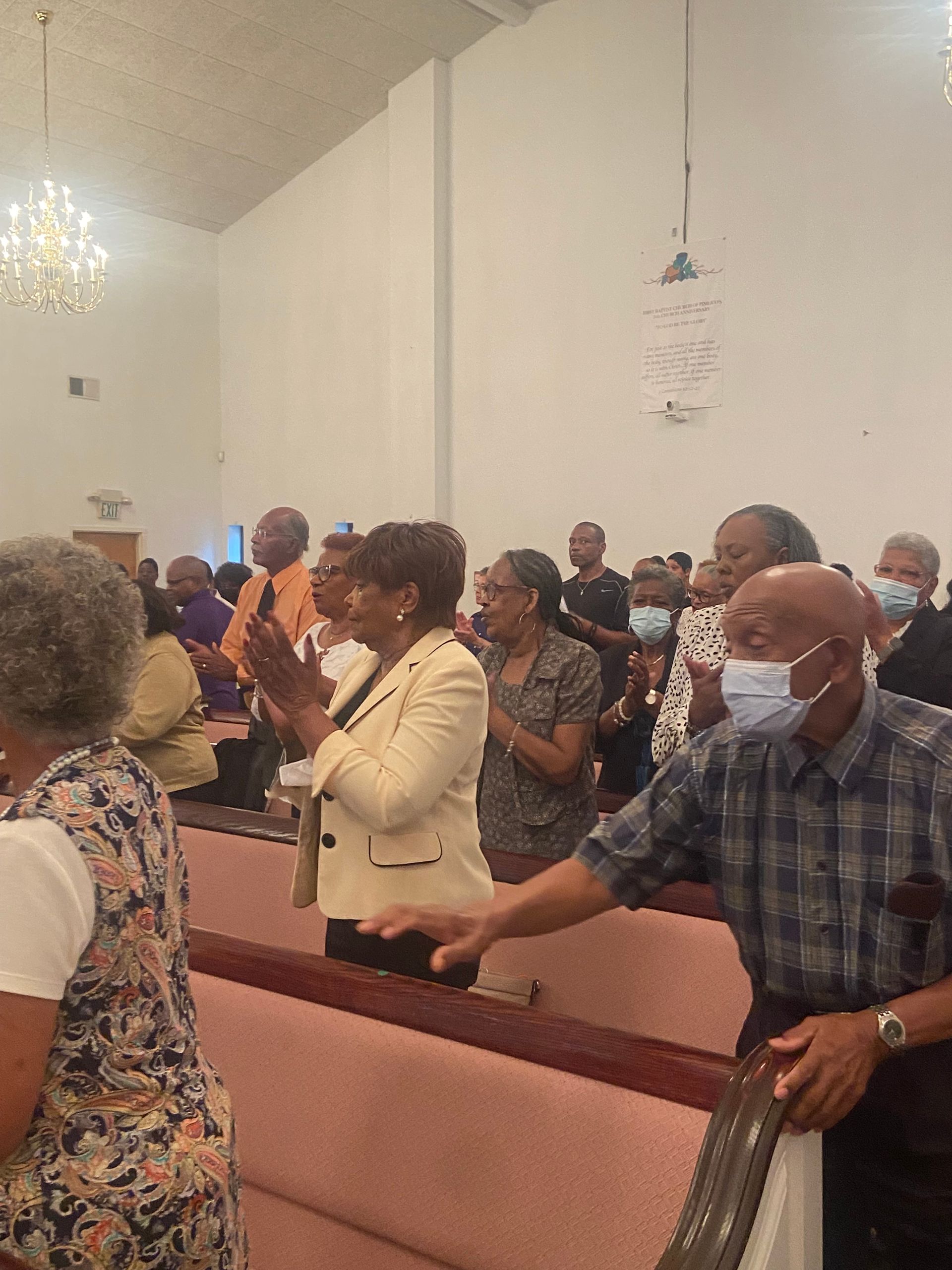 A group of people wearing face masks are standing in a church.