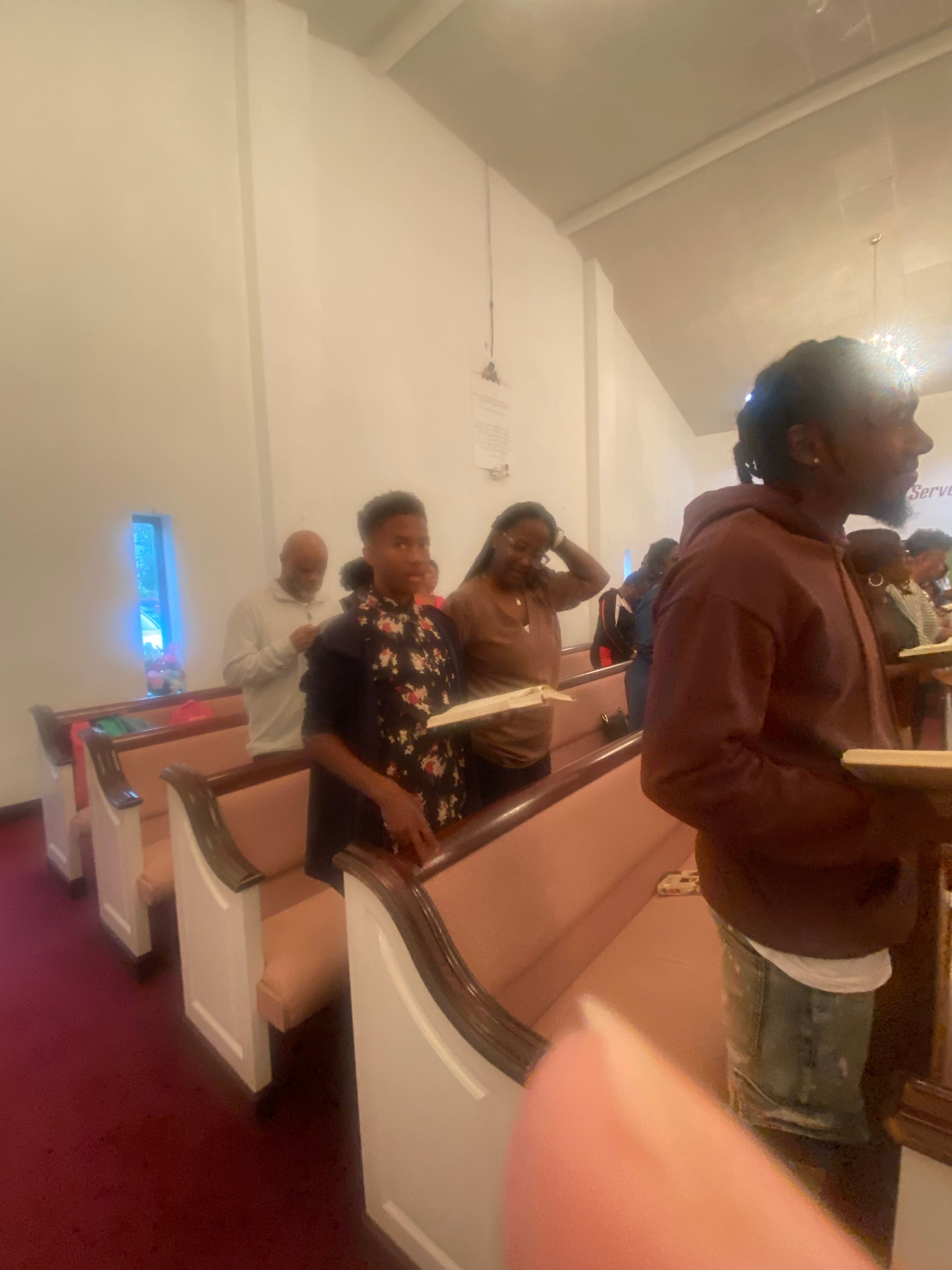 A group of people are sitting in a church holding bible