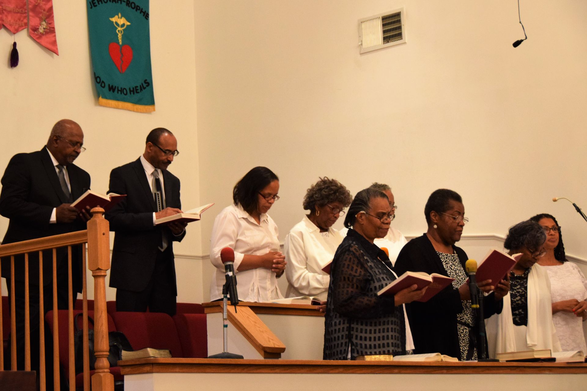 A group of people are standing in a church reading bible