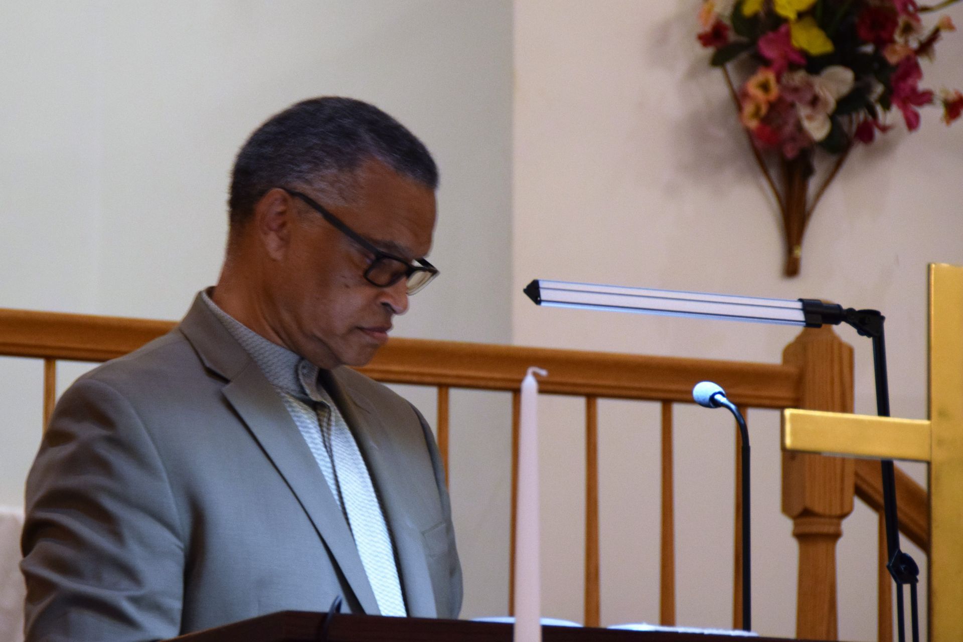 A man in a suit is sitting at a podium in front of a microphone.