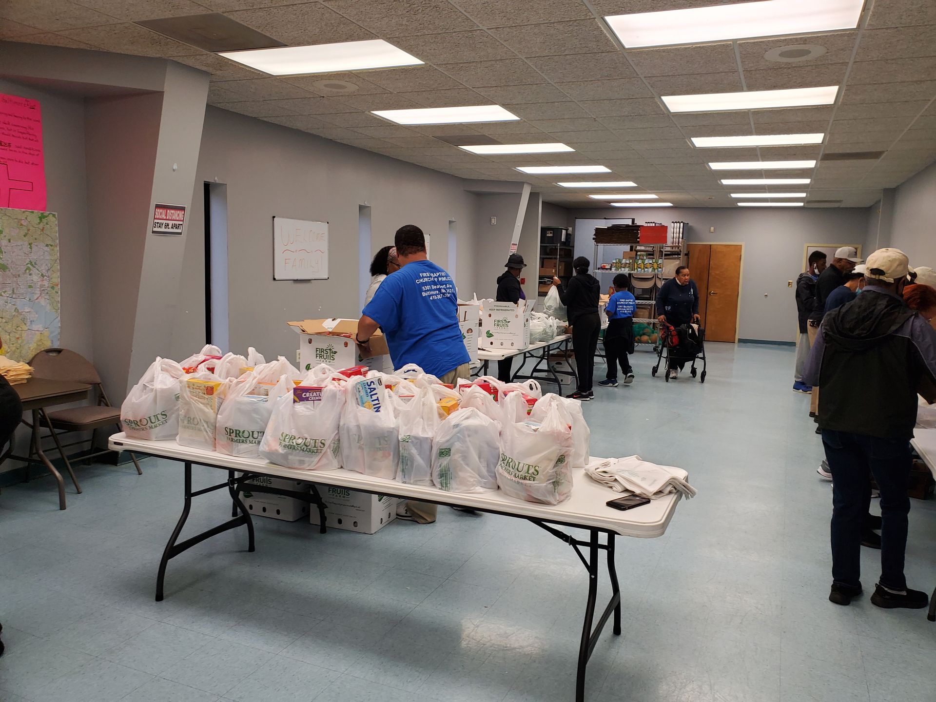 A group of people are standing around a table filled with bags of food.