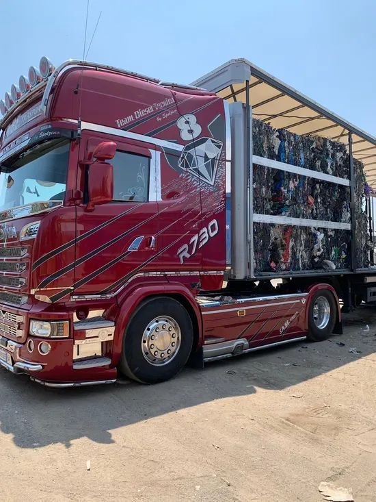 Camion Volvo rosso con cassone coperto parcheggiato all'aperto sotto il sole.