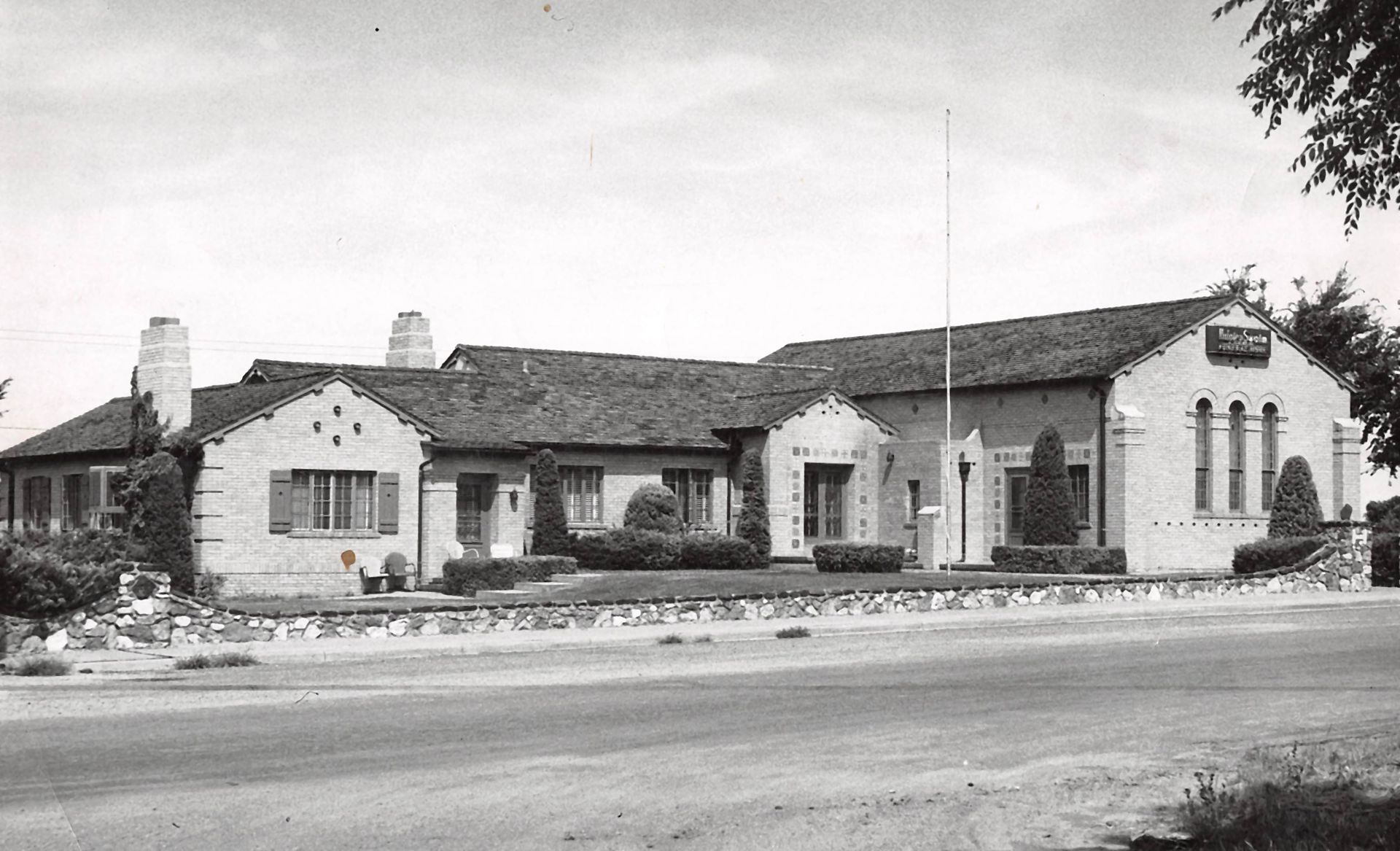 Black vintage car parked outdoors, front door open, tree background.