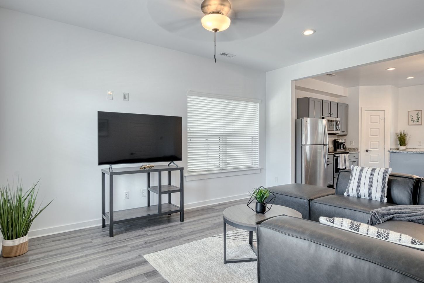 Living room with gray sectional, TV, and kitchen view.