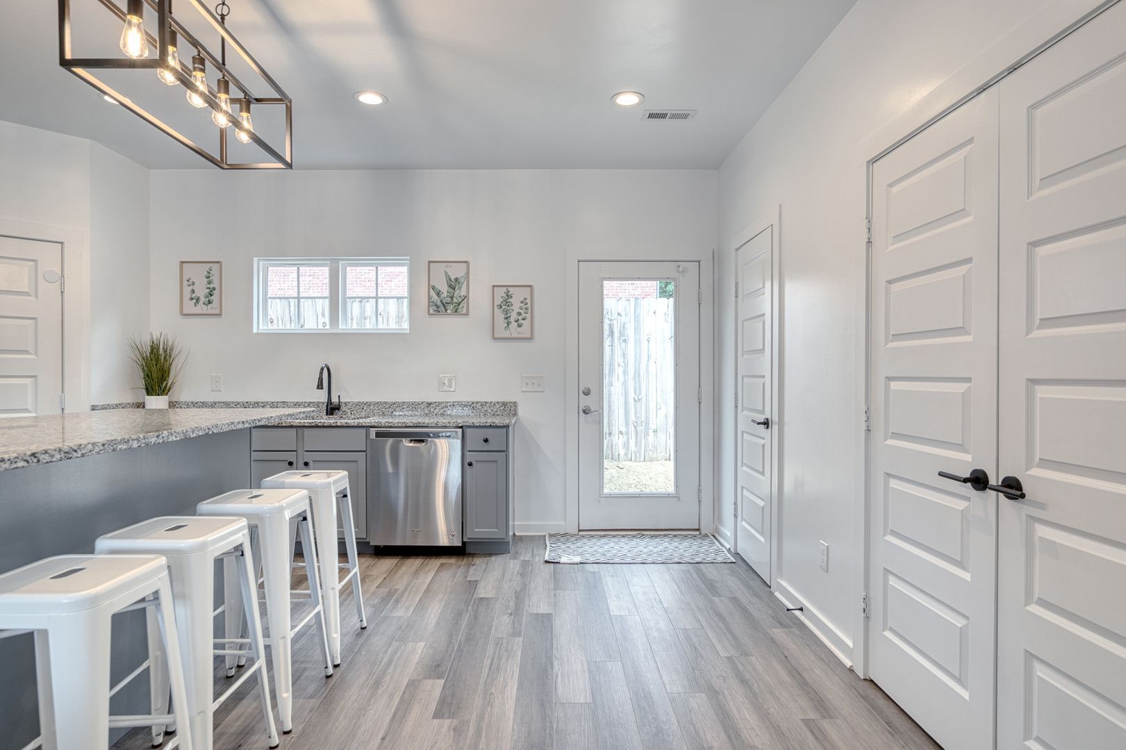 Modern kitchen with bar seating, white cabinets, stainless steel appliances, and door to outdoors.
