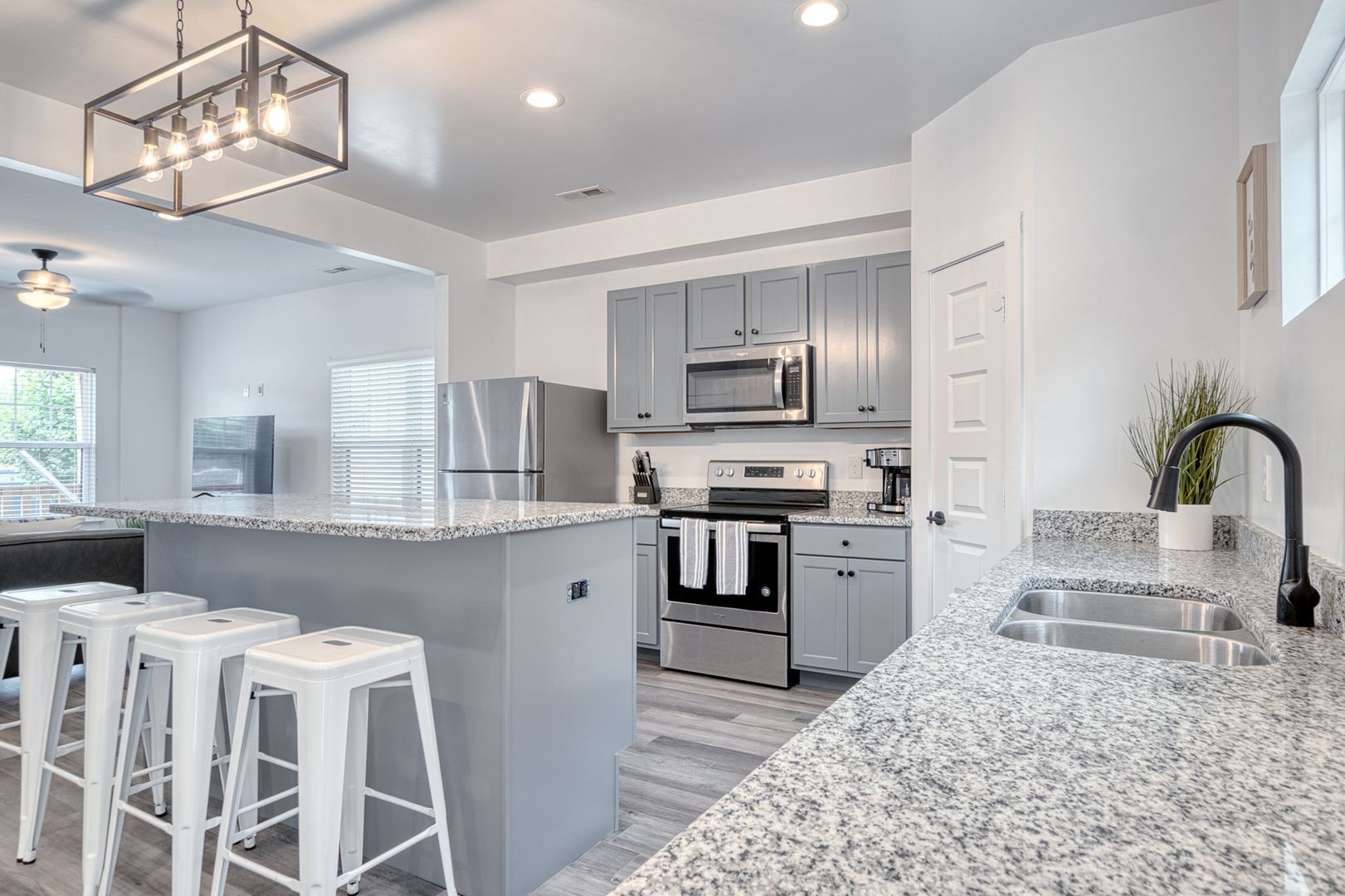 Modern kitchen with grey cabinets, stainless steel appliances, and granite countertops.