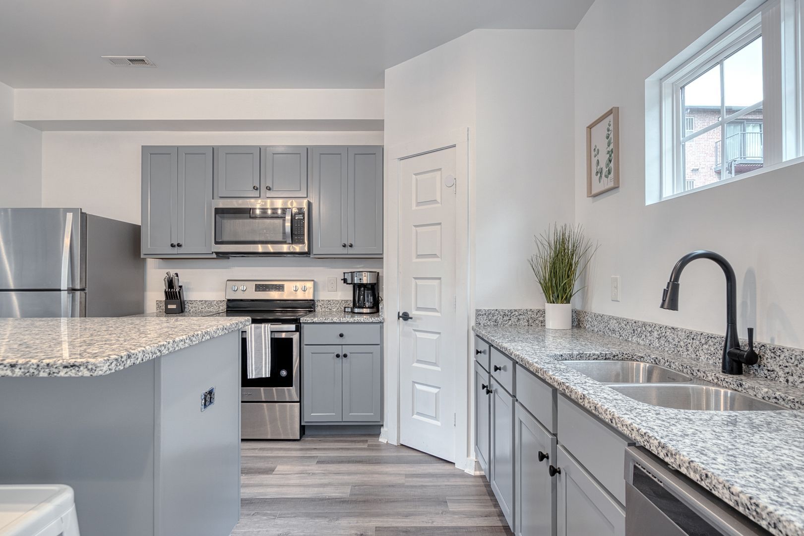 Gray and stainless steel kitchen with granite countertops, cabinets, and island.