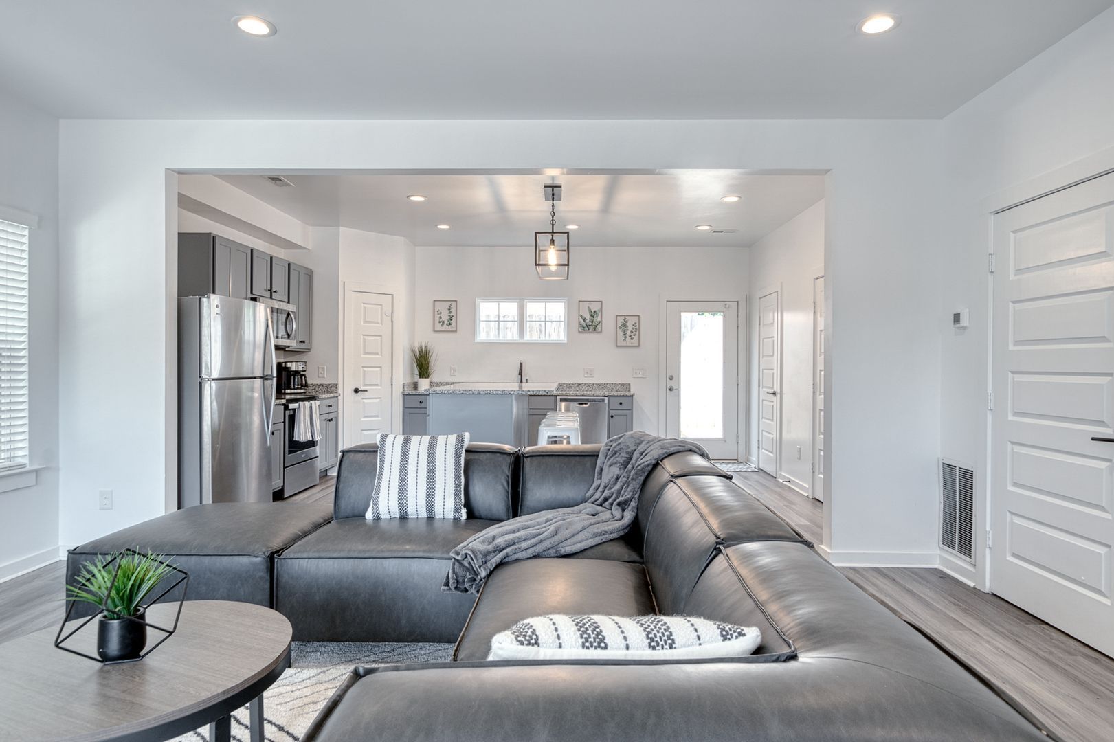 Modern living room with gray sectional sofa, open to a kitchen.