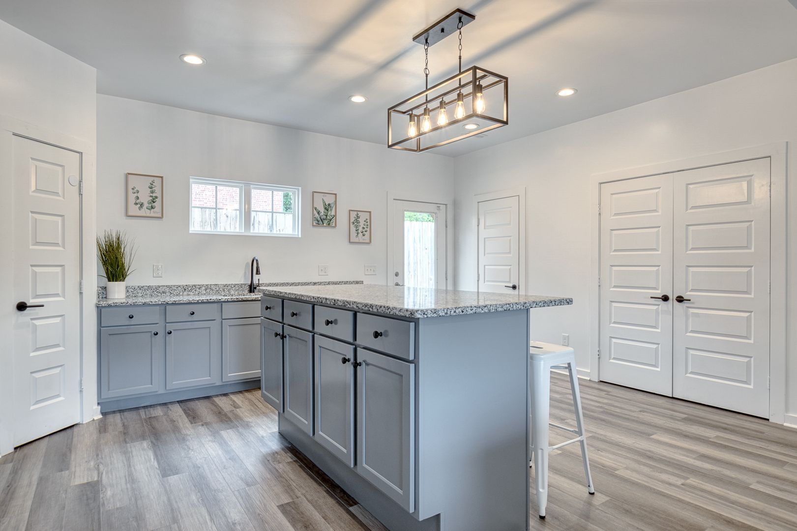 Modern kitchen with gray cabinets, island, granite counters, and hardwood floors.