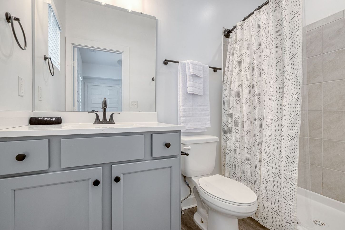 Gray and white bathroom with a vanity, toilet, and shower/tub area.