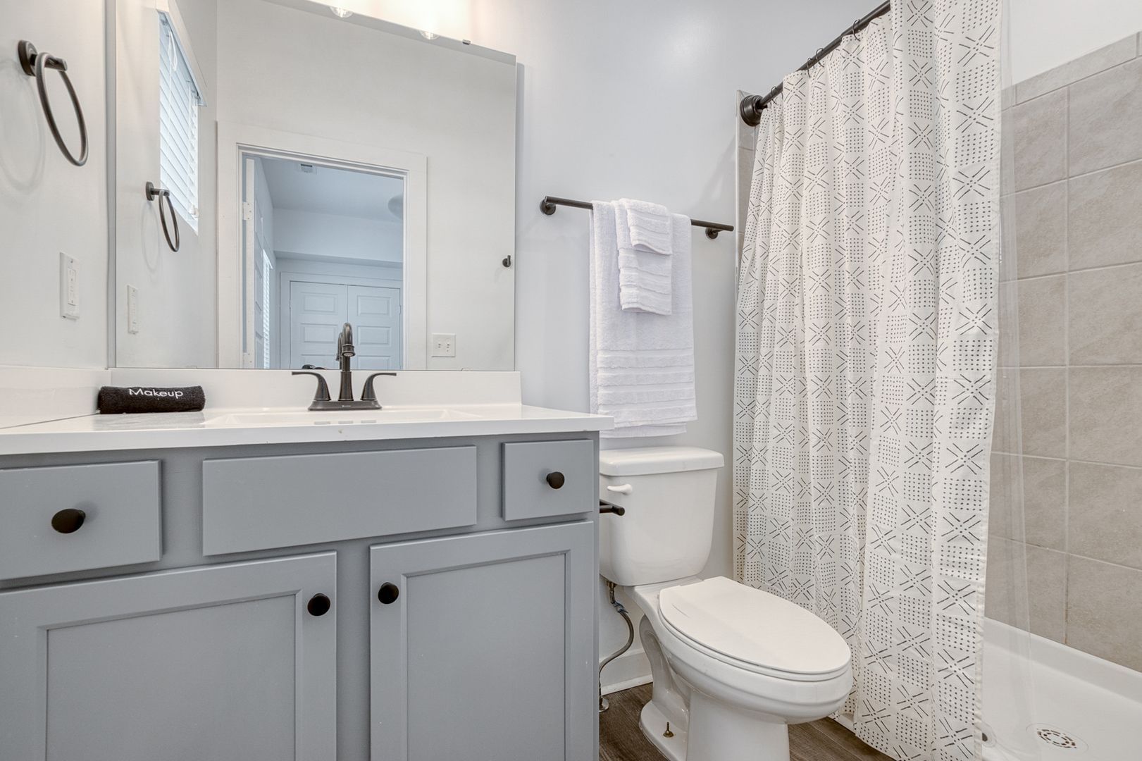 Gray and white bathroom with a vanity, toilet, and shower/tub area.