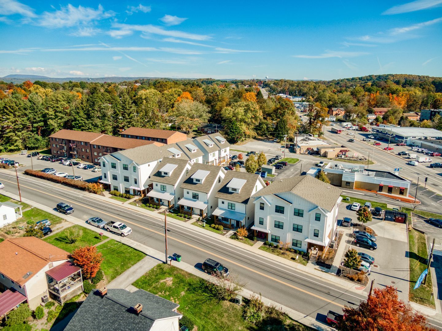 Aerial view of townhouses and surrounding businesses, a sunny day with fall foliage.