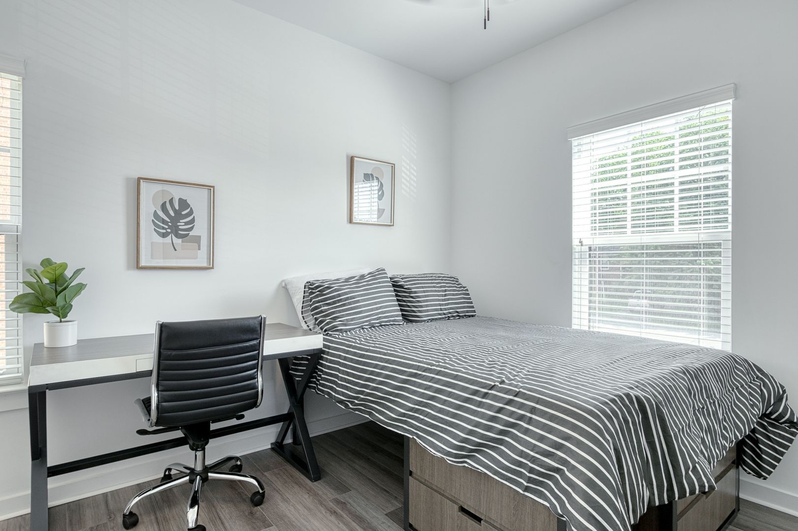 Bedroom with bed, desk, and window. Gray and white color scheme.