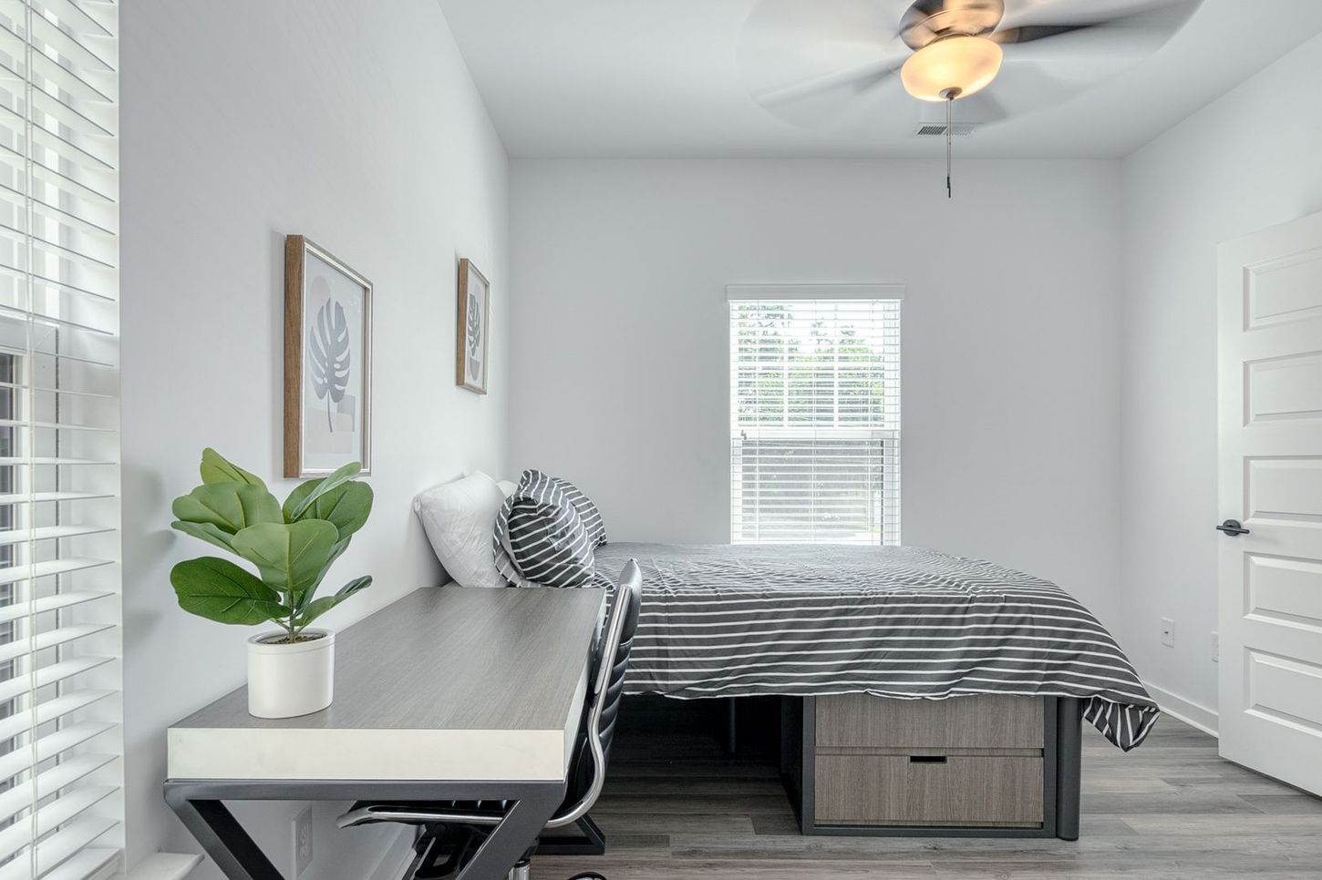 Bedroom with bed, desk, window, and white walls. Modern, bright interior.
