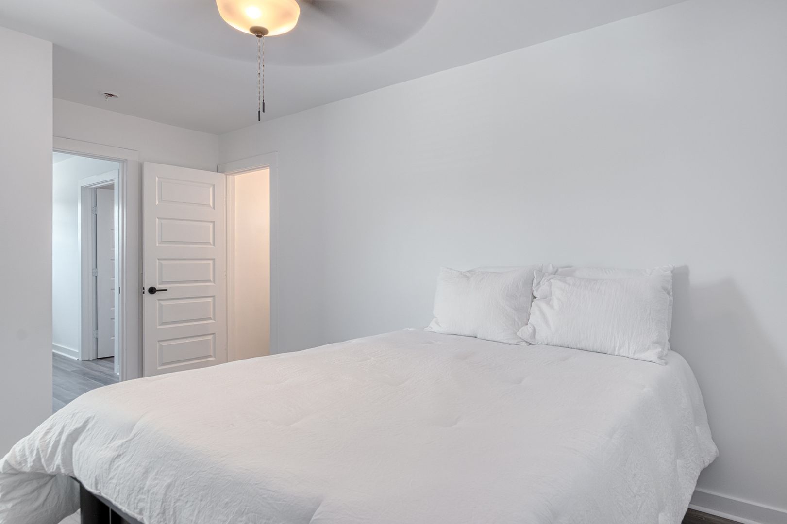 White bedroom with a bed, pillows, and a door.