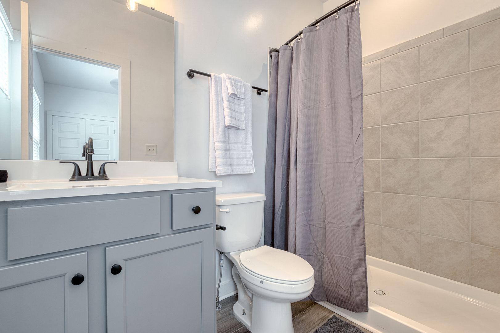 Gray and white bathroom with a vanity, toilet, and shower/tub.