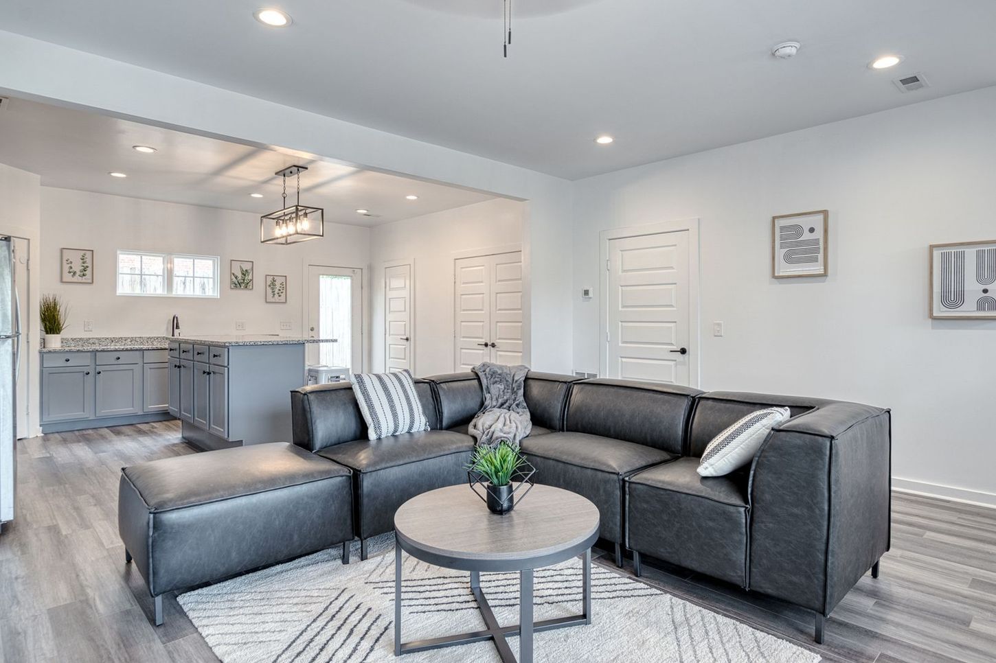 Modern living room with gray sectional, coffee table, and open kitchen.