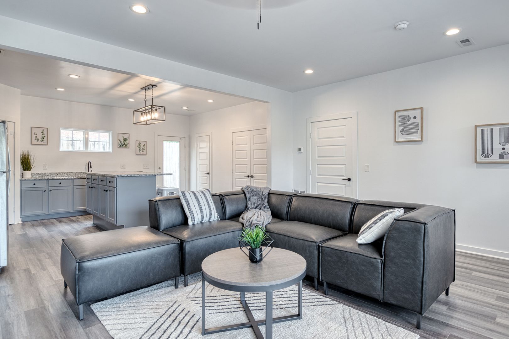 Modern living room with gray sectional, coffee table, and open kitchen.