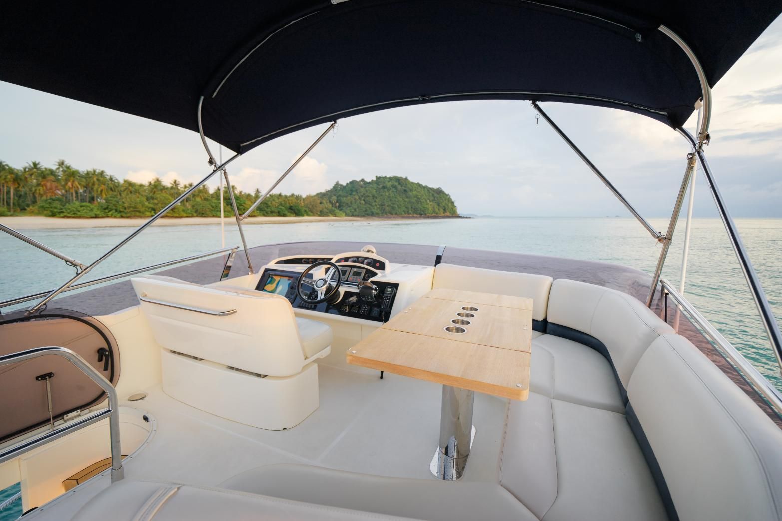 Interior of a pontoon boat with seating, a table, and the ocean in the background.