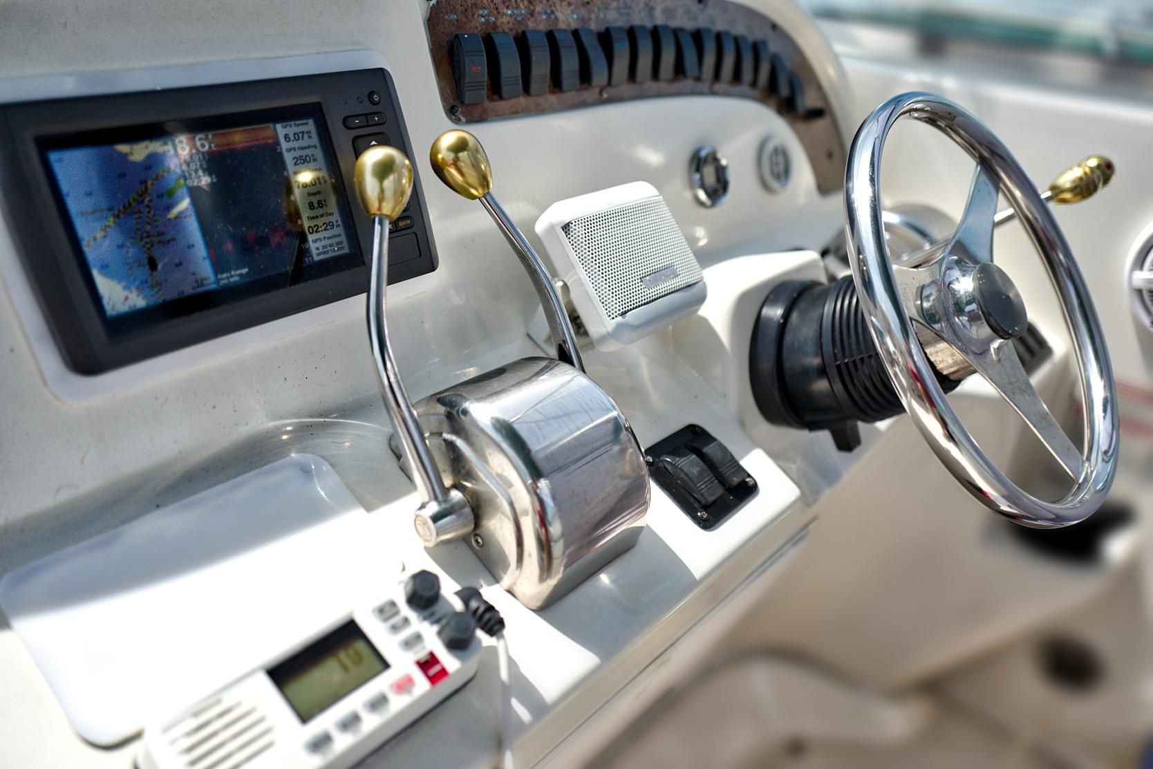 Boat dashboard with a steering wheel, gauges, and controls.