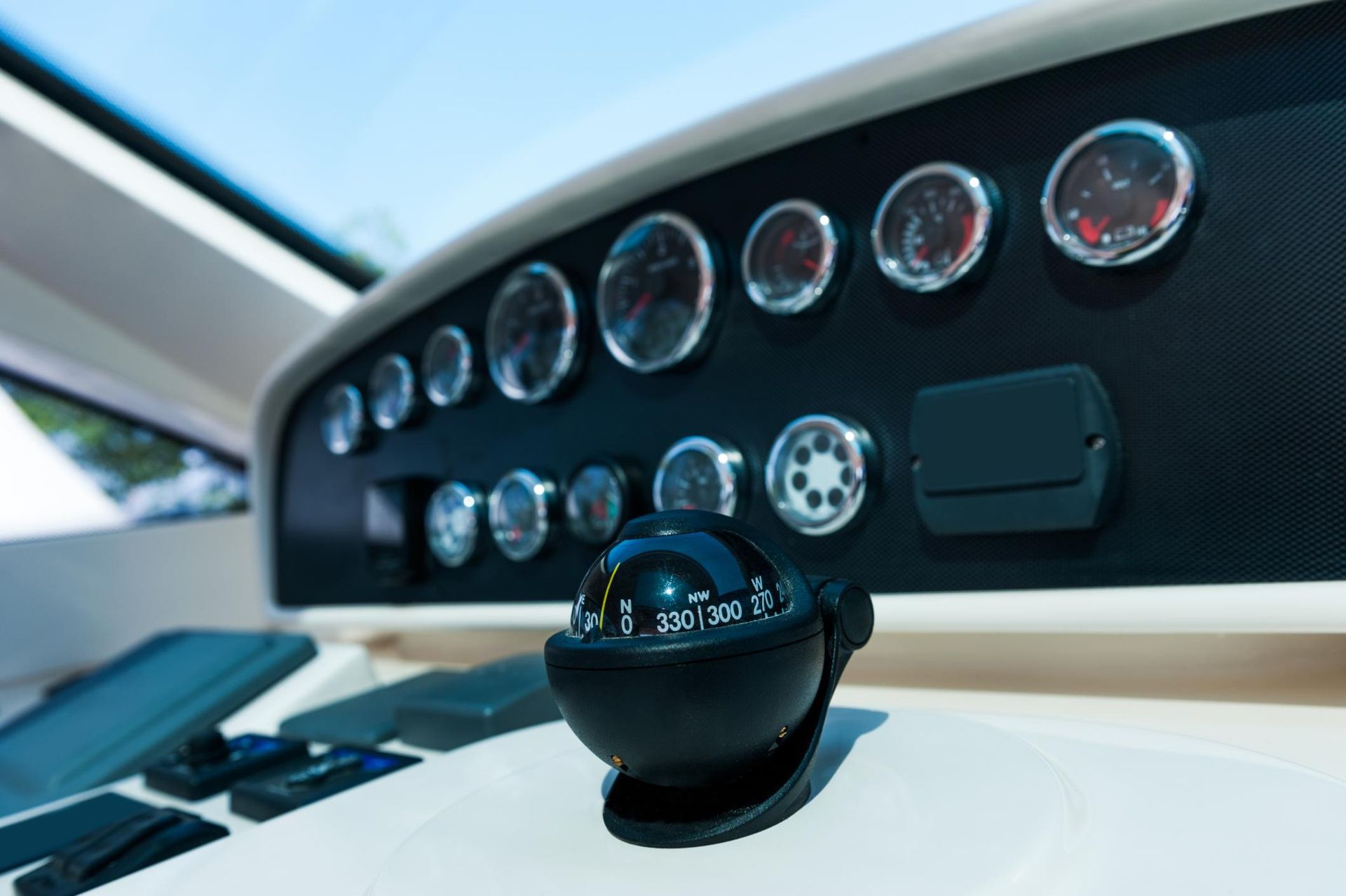 Dashboard of a boat with gauges and a compass, viewed at an angle.