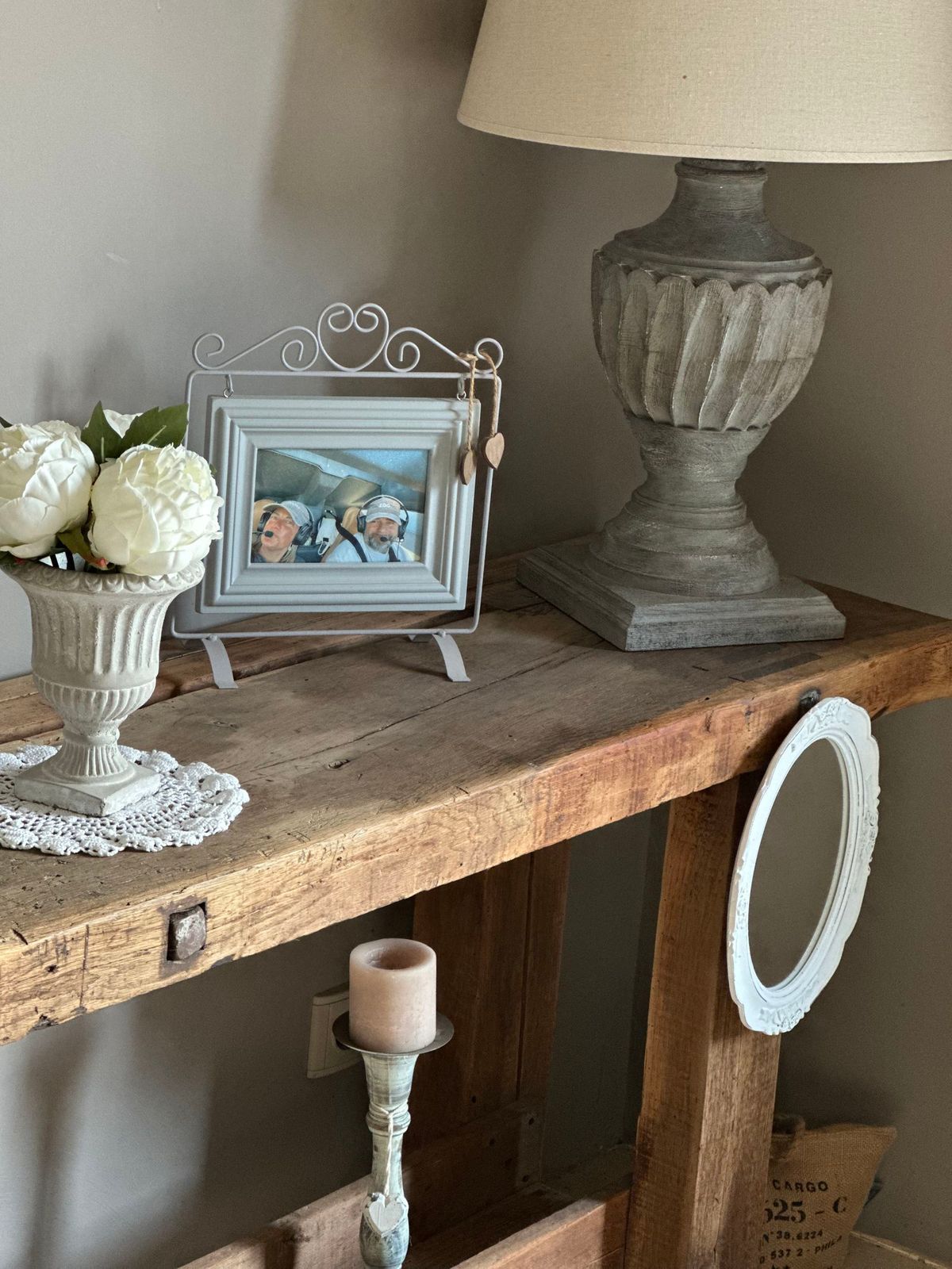 Console en bois avec décoration : lampe, tableau encadré, fleurs, bougie et miroir.