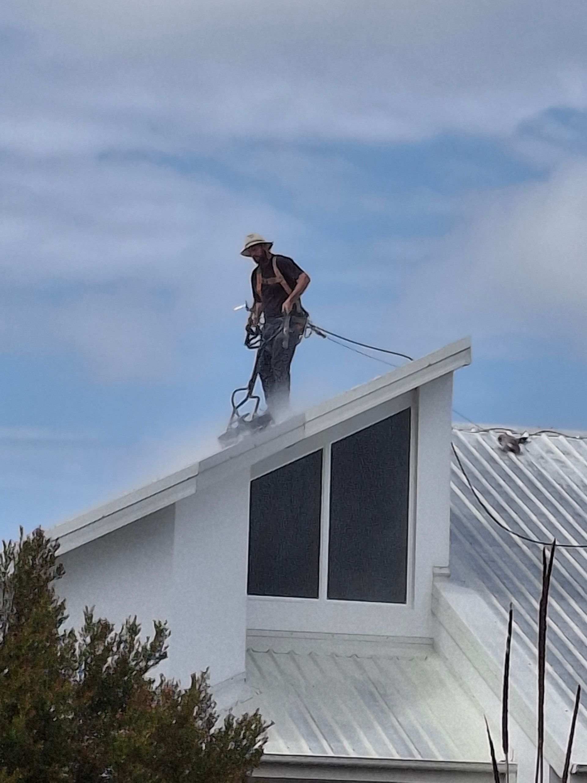 A Man is Painting a Pink Roof With a Sprayer — A-Z Property Painting In Karuah, NSW