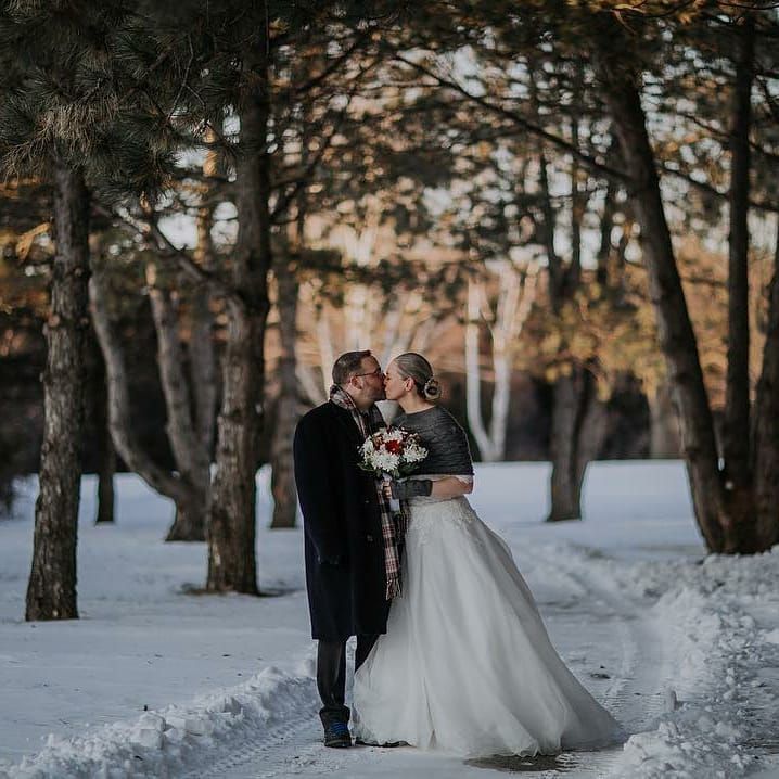 A bride and groom are kissing in the snow.