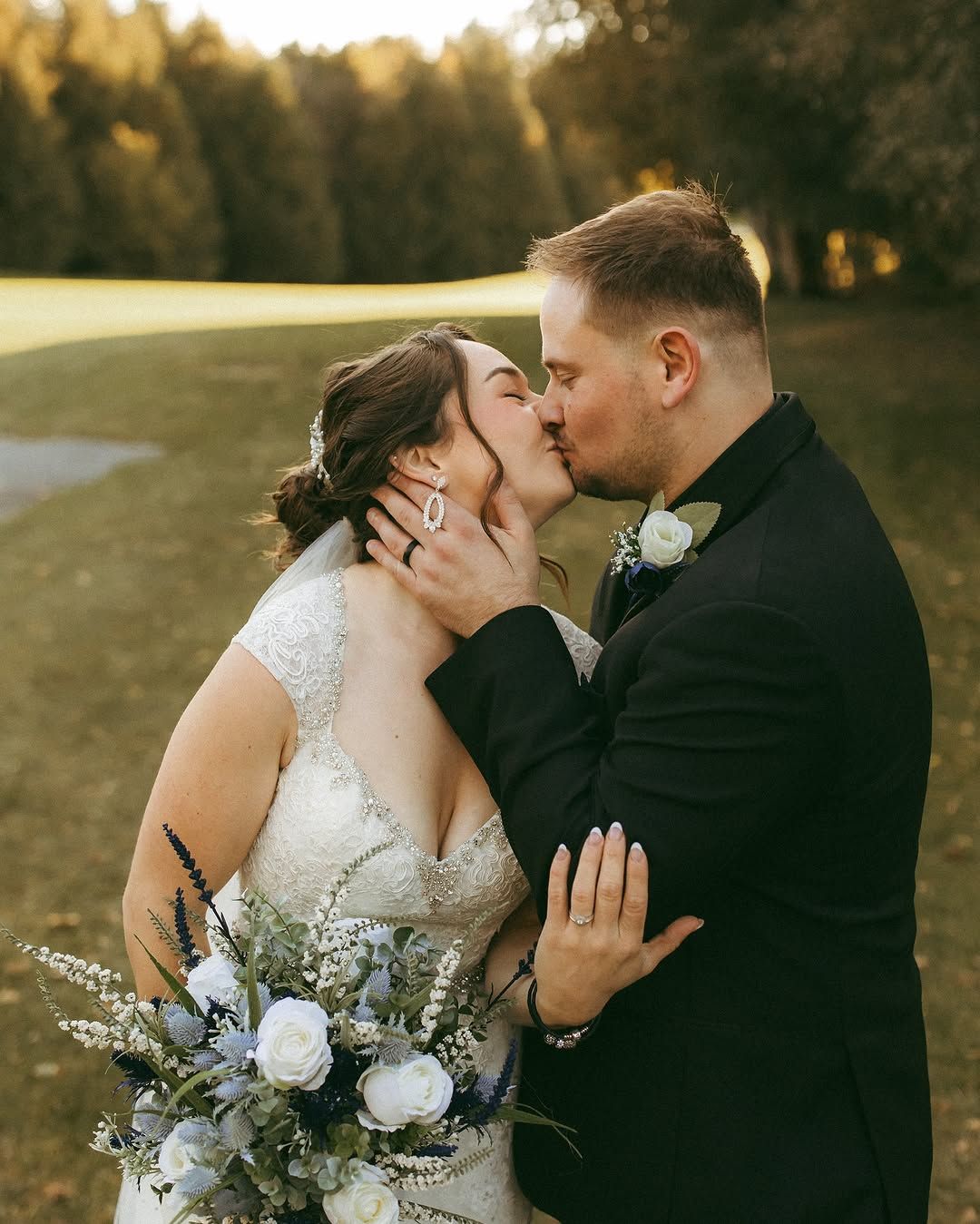 A bride and groom kissing on their wedding day on a golf course.