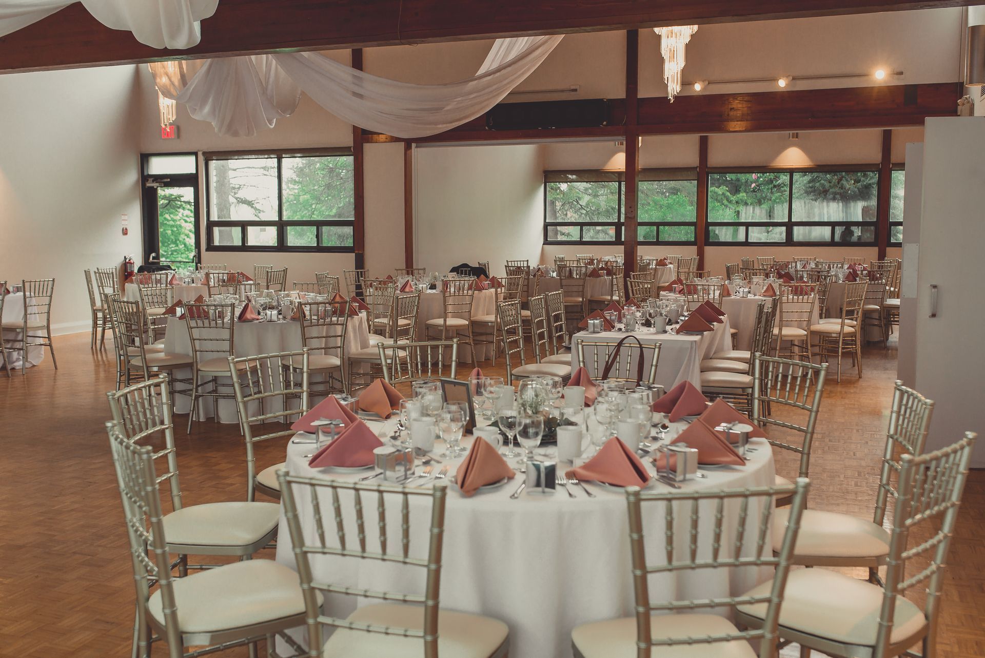 A large room with tables and chairs set up for a wedding reception.