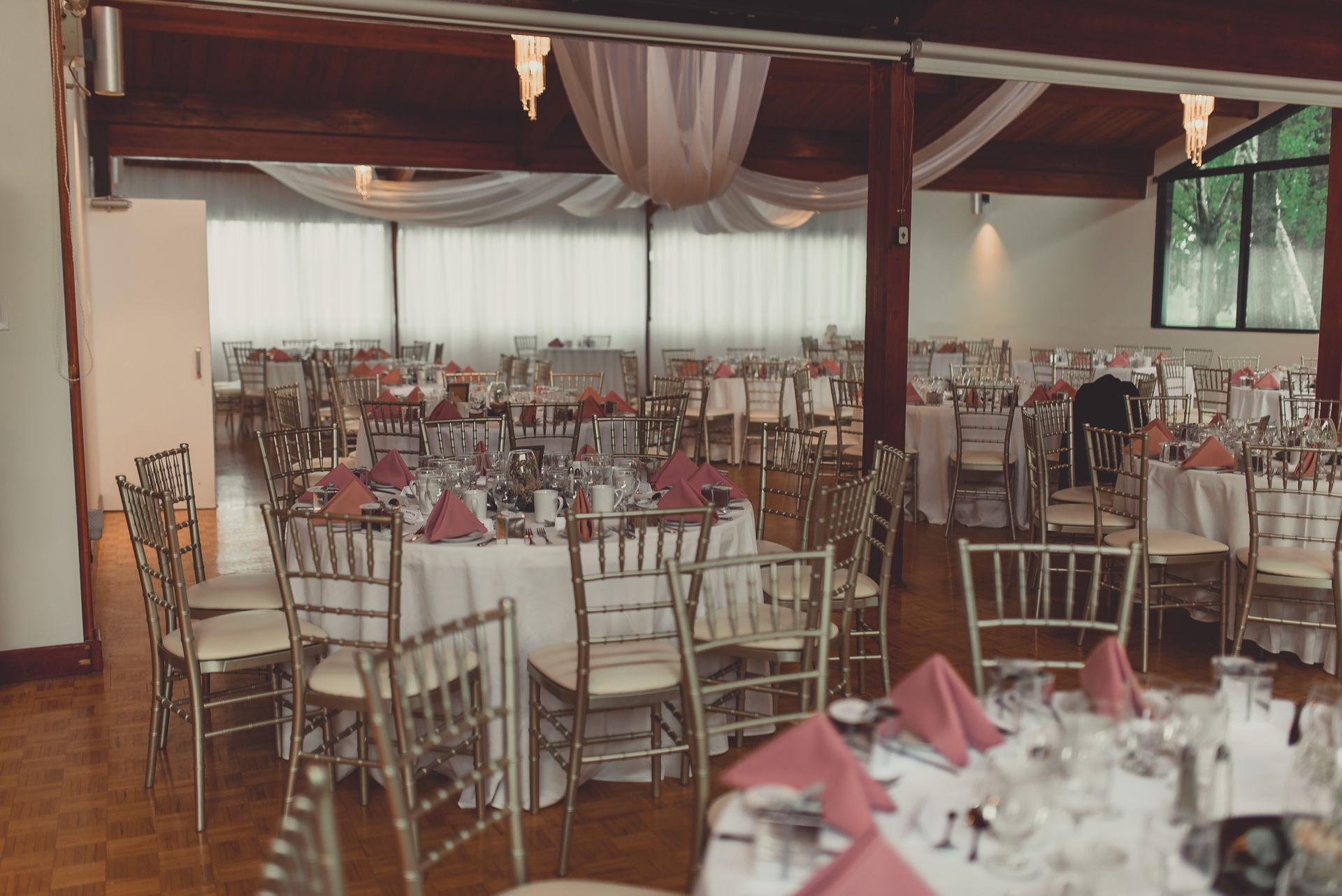 A large room with tables and chairs set up for a wedding reception.